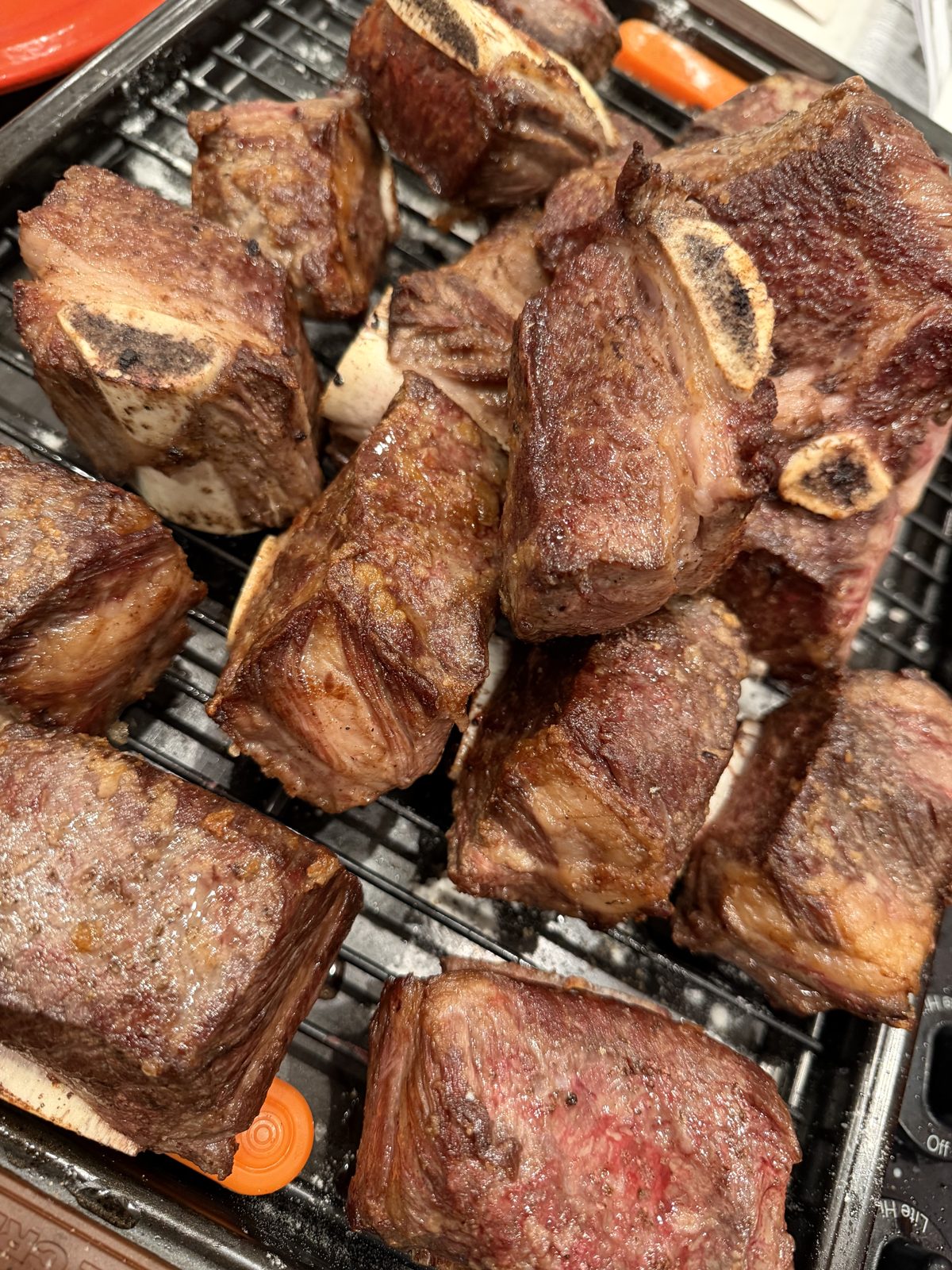 Deeply seared bone-in short ribs on a rack, ready to braise