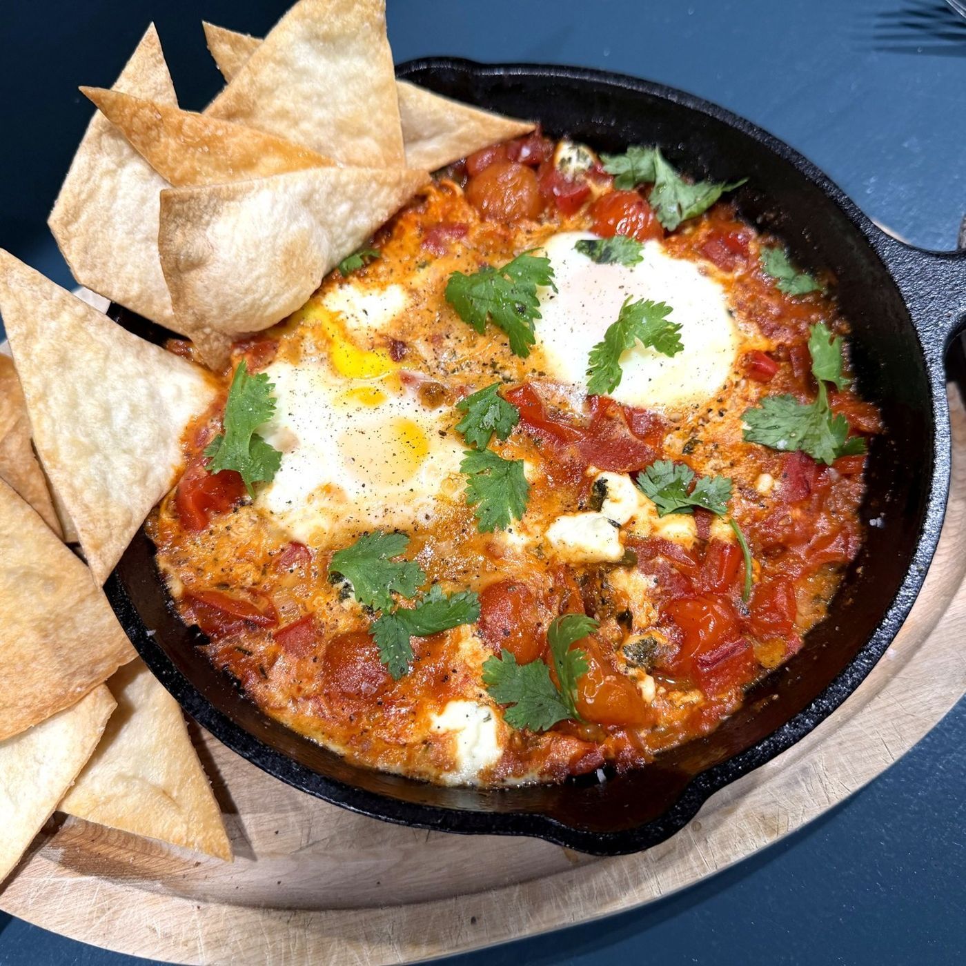 Mexican-inspired shakshuka with feta and cilantro in a cast-iron pan, with tortilla chips