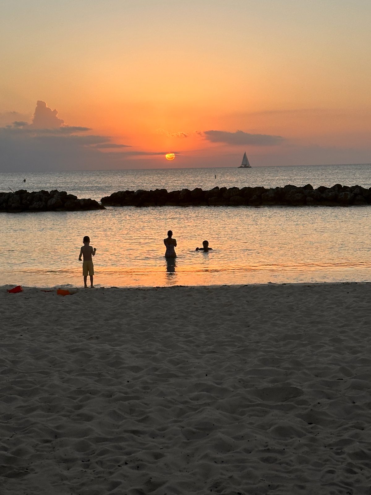 People swimming at sunset inside the rock breakwater at Sunset Cove