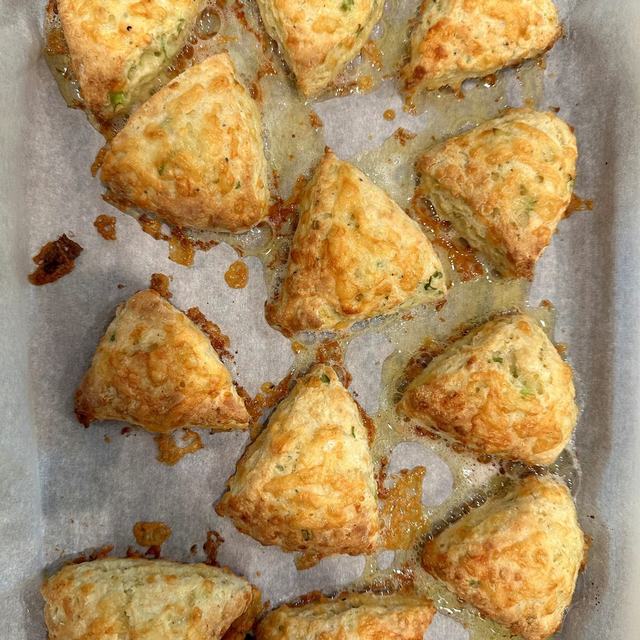 Cheddar chive scones on a baking tray with crispy cheese edges