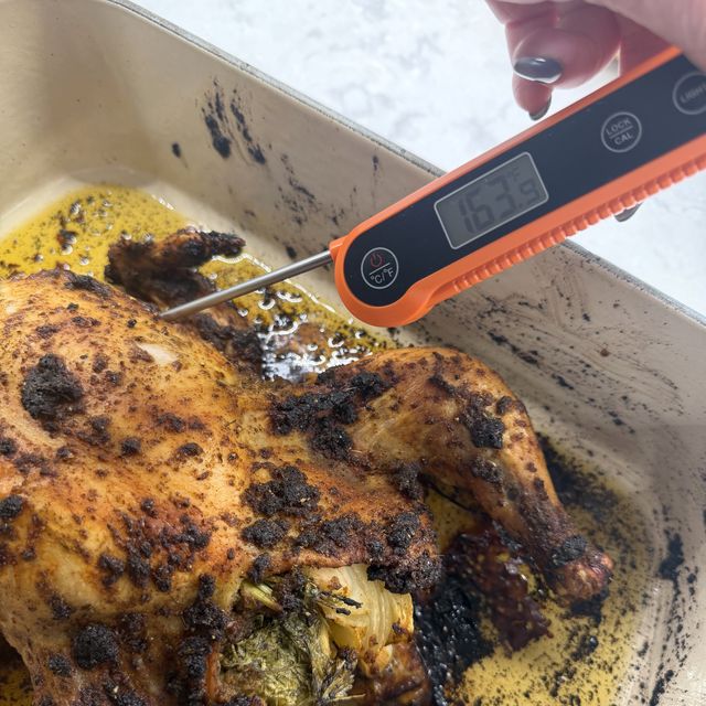 An orange instant-read thermometer in a roast chicken, reading 163 degrees